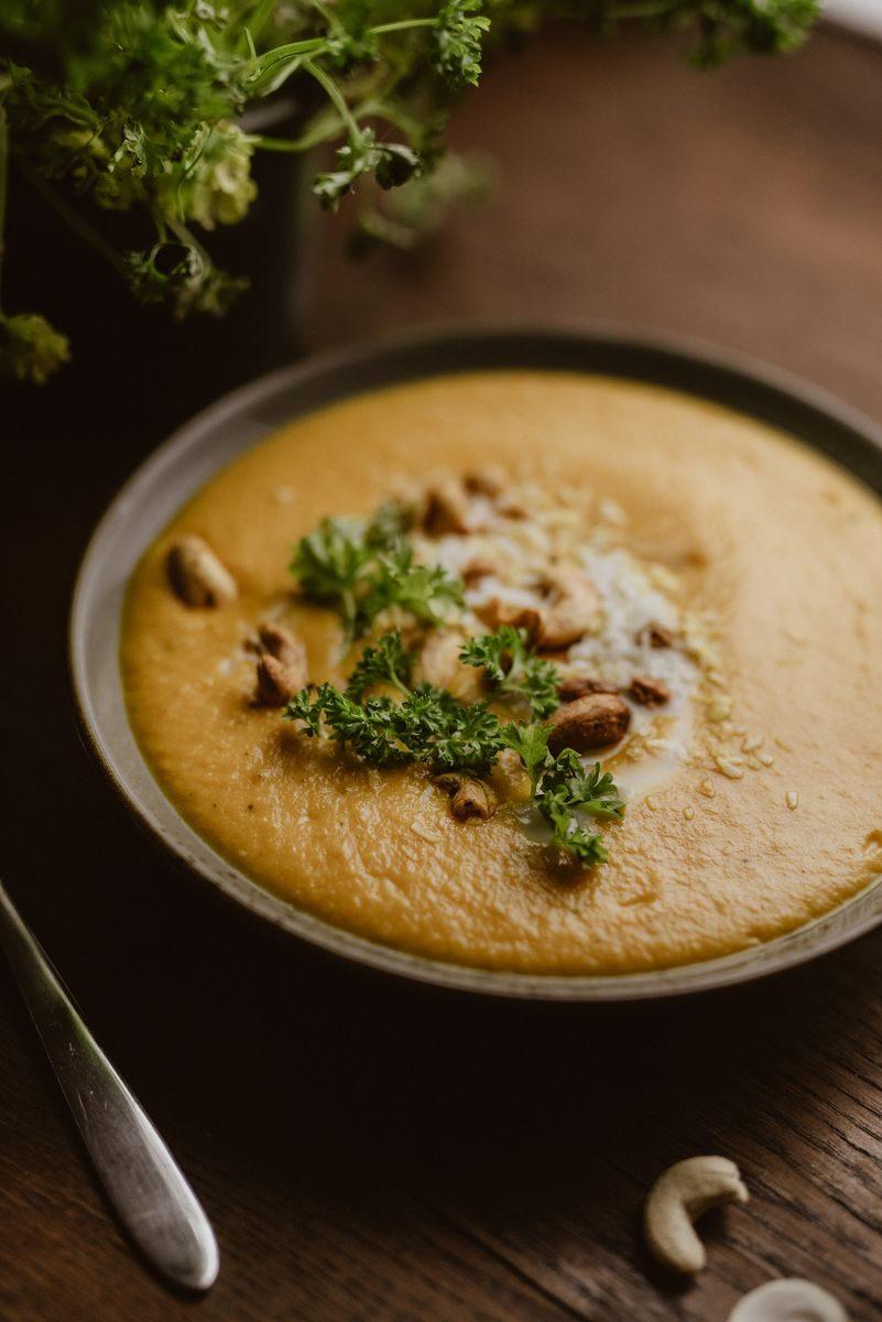 A warm and creamy cashew soup garnished with fresh parsley, perfect for a healthy meal.